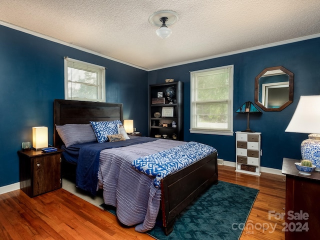 bedroom featuring ornamental molding, a textured ceiling, and hardwood / wood-style flooring