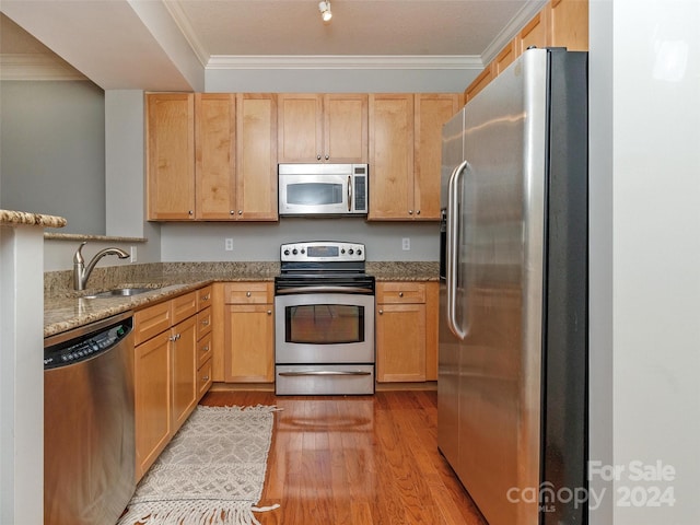 kitchen with sink, stainless steel appliances, light stone counters, light hardwood / wood-style flooring, and ornamental molding