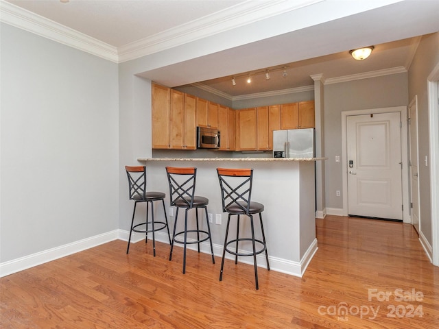 kitchen with crown molding, a breakfast bar area, light wood-type flooring, kitchen peninsula, and stainless steel appliances