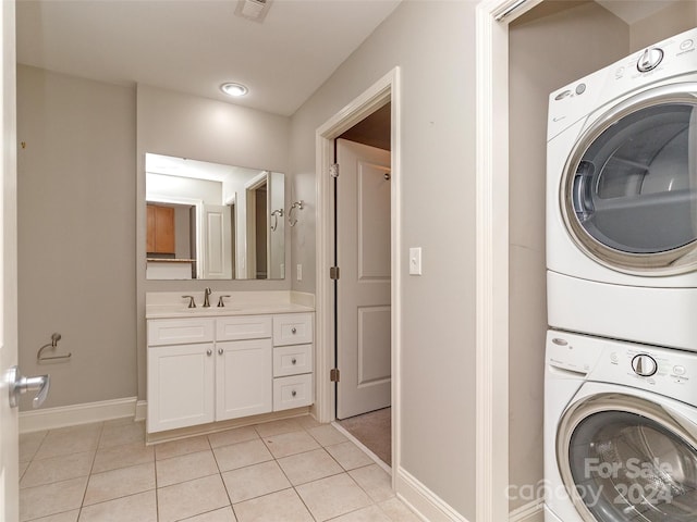 laundry room featuring light tile patterned flooring, stacked washer / drying machine, and sink