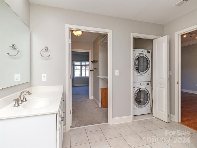 laundry room with light tile patterned floors, stacked washer / drying machine, and sink