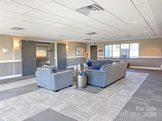 carpeted living room featuring elevator and a drop ceiling