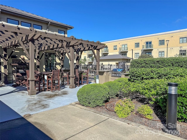 surrounding community with an outdoor kitchen, a pergola, and an outdoor bar