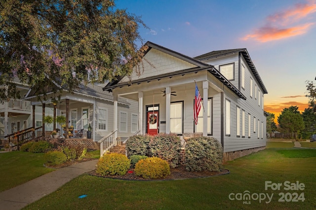 view of front of property with ceiling fan, a yard, and covered porch