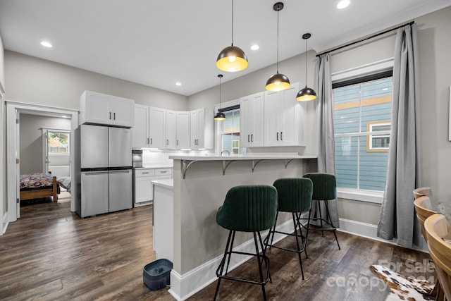 kitchen with white cabinets, a kitchen breakfast bar, kitchen peninsula, and stainless steel refrigerator