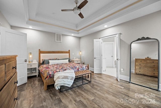 bedroom with a tray ceiling, ceiling fan, and hardwood / wood-style floors