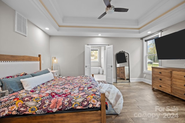 bedroom featuring a raised ceiling, multiple windows, and ceiling fan