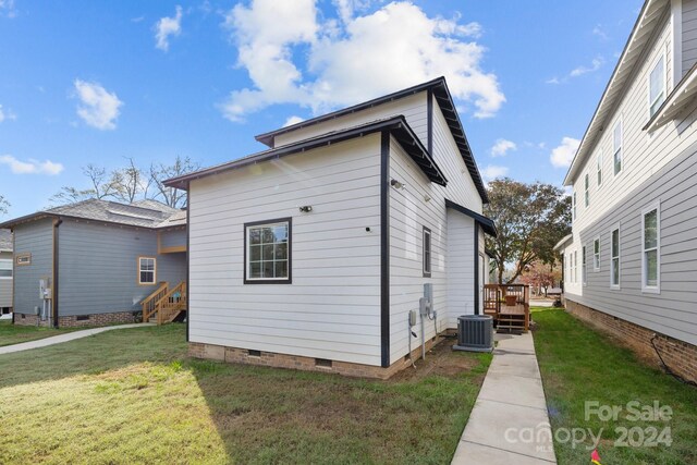 view of side of home with a lawn, central AC unit, and a wooden deck