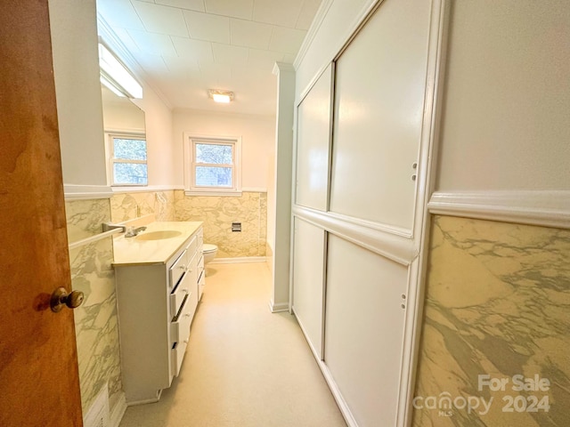 bathroom featuring vanity, toilet, crown molding, and tile walls