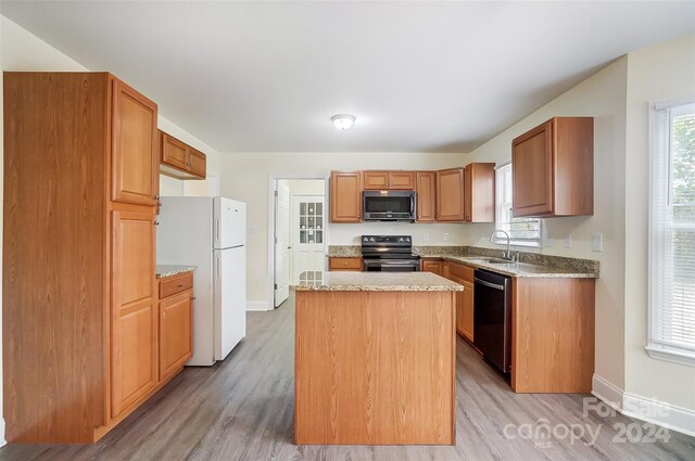 kitchen with sink, a center island, black appliances, and light hardwood / wood-style floors