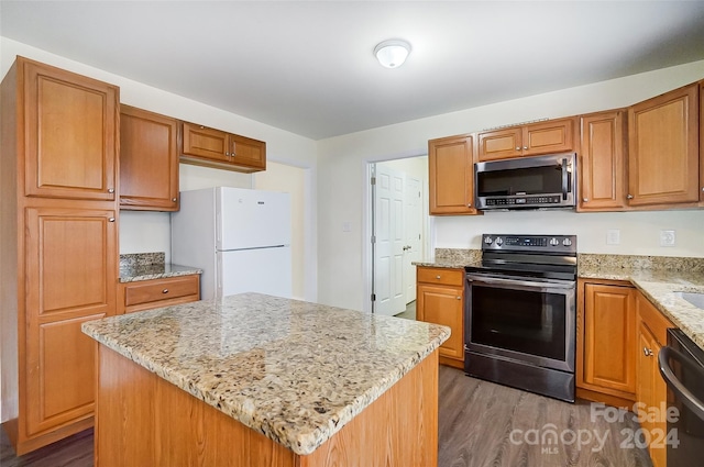 kitchen featuring a center island, dark hardwood / wood-style flooring, light stone counters, and appliances with stainless steel finishes