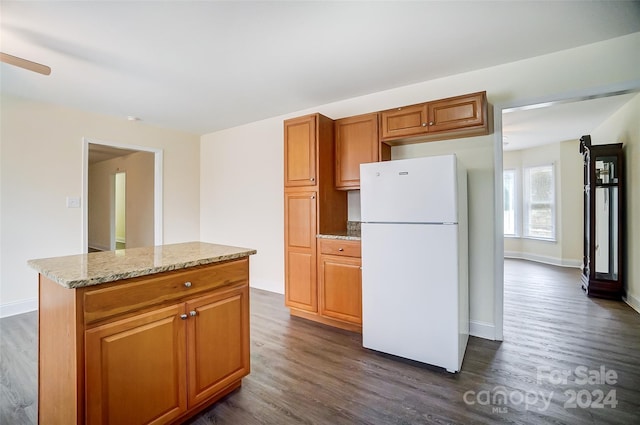 kitchen with white fridge, dark hardwood / wood-style flooring, and light stone countertops