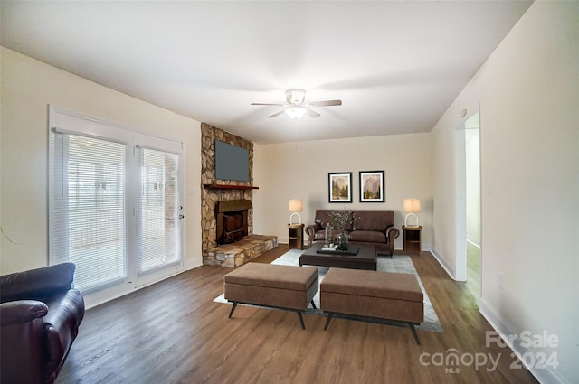 living room with hardwood / wood-style flooring, ceiling fan, and a stone fireplace