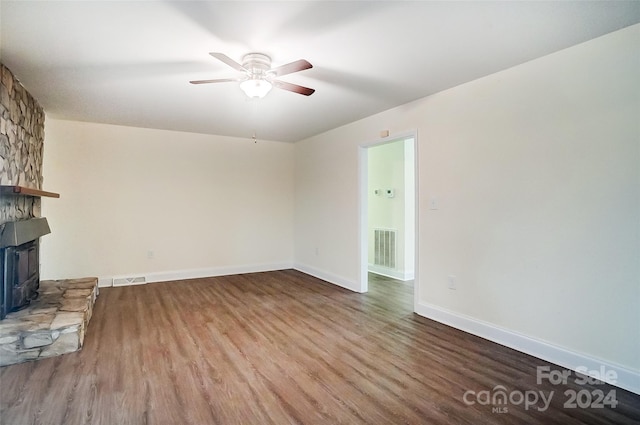 unfurnished living room with ceiling fan, light hardwood / wood-style floors, and a wood stove