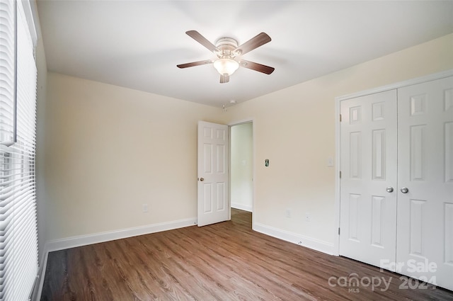 unfurnished bedroom with wood-type flooring, a closet, and ceiling fan