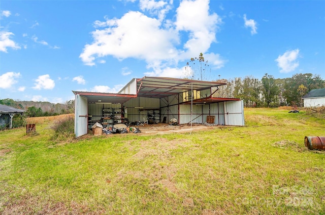 back of property featuring an outdoor structure and a yard