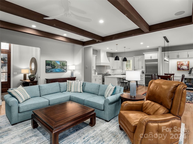 living room featuring ceiling fan, beam ceiling, and light hardwood / wood-style flooring