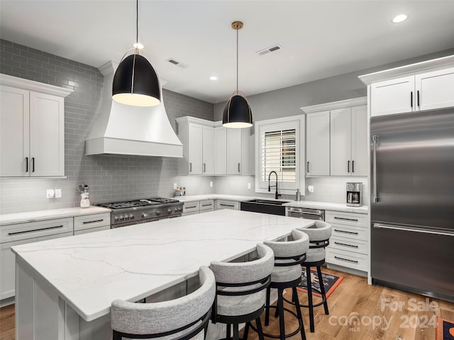 kitchen with sink, appliances with stainless steel finishes, decorative light fixtures, light hardwood / wood-style floors, and white cabinetry