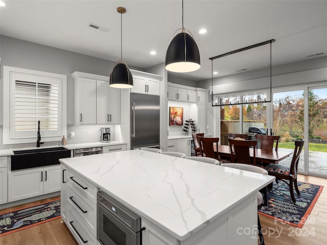 kitchen featuring white cabinetry, sink, light hardwood / wood-style flooring, backsplash, and built in appliances