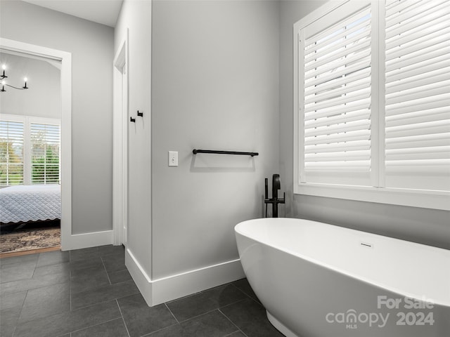 bathroom featuring a bathing tub, tile patterned floors, and a chandelier