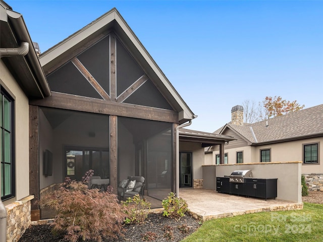 rear view of property featuring an outdoor kitchen and a patio area