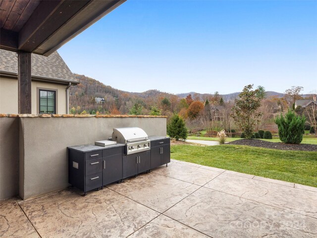 view of patio with a mountain view, an outdoor kitchen, and a grill