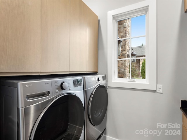 clothes washing area with washer and dryer and cabinets