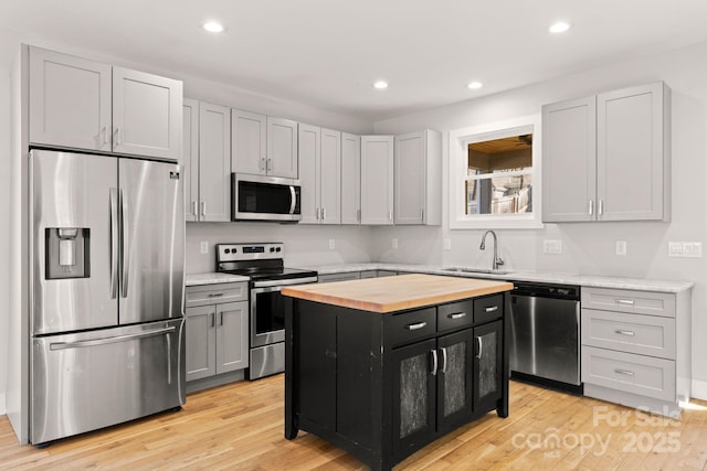 kitchen with sink, light hardwood / wood-style flooring, appliances with stainless steel finishes, butcher block counters, and a center island