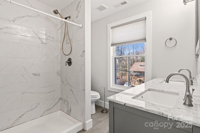 bathroom with vanity, toilet, and tiled shower