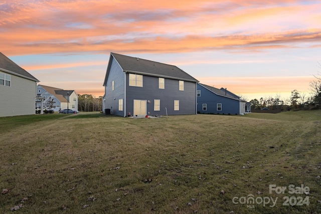 back house at dusk with a lawn