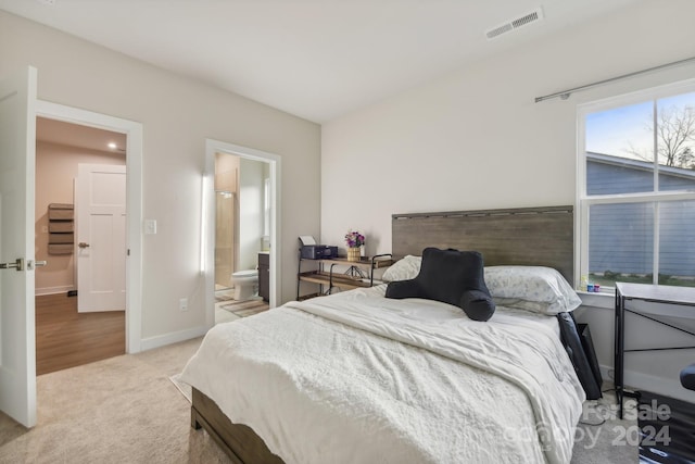 bedroom featuring ensuite bathroom and light colored carpet