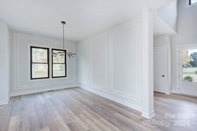 unfurnished dining area featuring light hardwood / wood-style floors and an inviting chandelier