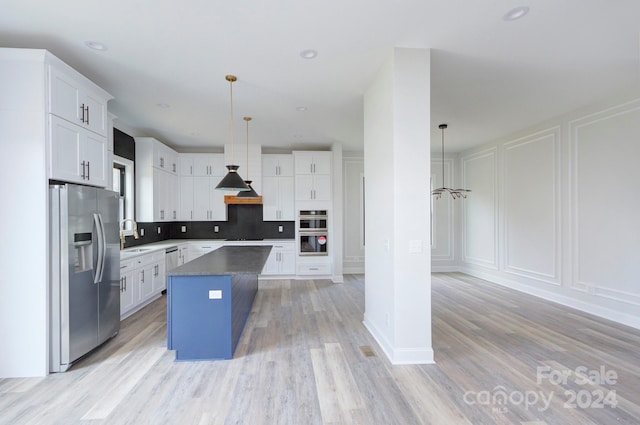 kitchen featuring a center island, hanging light fixtures, stainless steel appliances, light hardwood / wood-style floors, and white cabinets