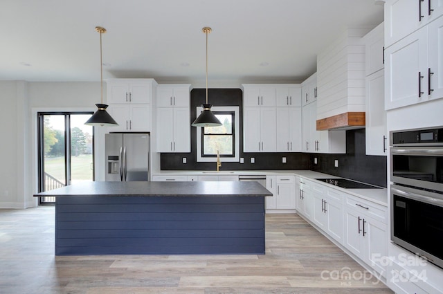 kitchen with appliances with stainless steel finishes, a center island, white cabinetry, and a healthy amount of sunlight