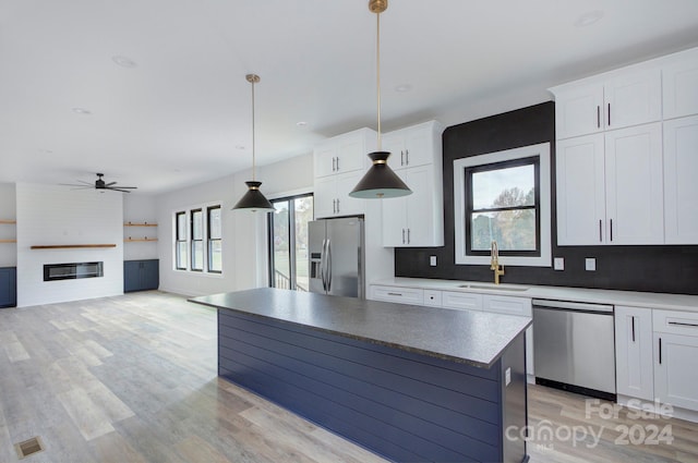 kitchen featuring white cabinets, sink, hanging light fixtures, a kitchen island, and stainless steel appliances