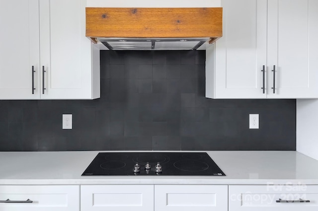 kitchen featuring white cabinets, black electric stovetop, decorative backsplash, and range hood