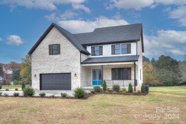 view of front of home with covered porch, a front yard, and a garage