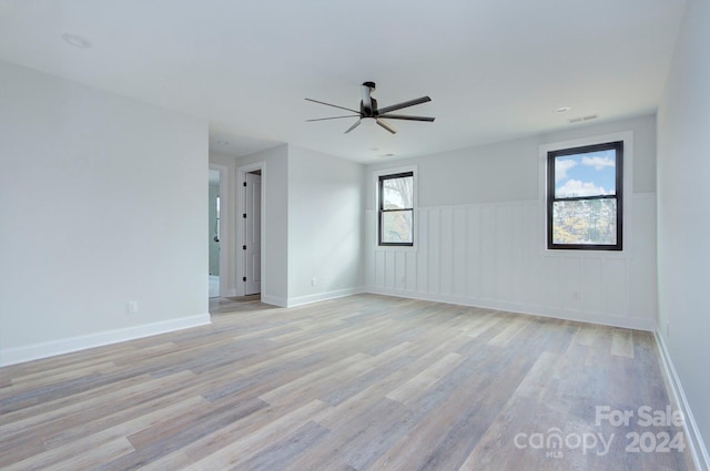 spare room with ceiling fan, light wood-type flooring, and a wealth of natural light