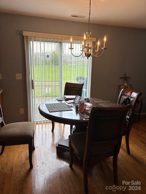 dining space with hardwood / wood-style flooring and an inviting chandelier