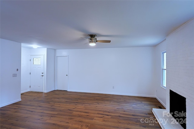 unfurnished living room with a fireplace, ceiling fan, and dark wood-type flooring