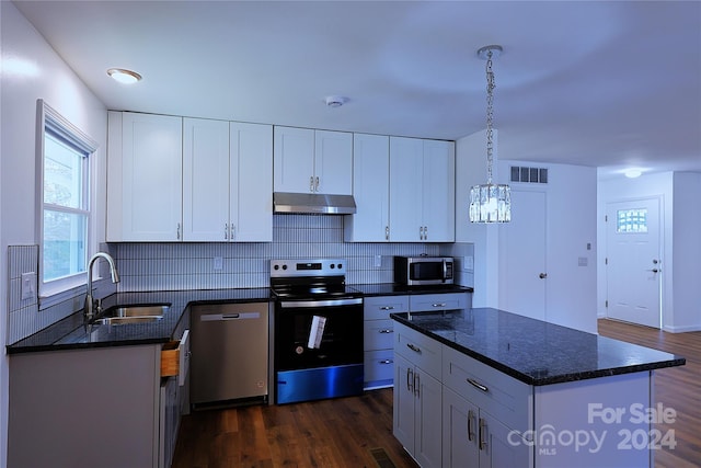 kitchen featuring appliances with stainless steel finishes, dark hardwood / wood-style flooring, sink, pendant lighting, and white cabinets