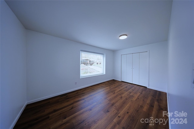 unfurnished bedroom with a closet and dark wood-type flooring