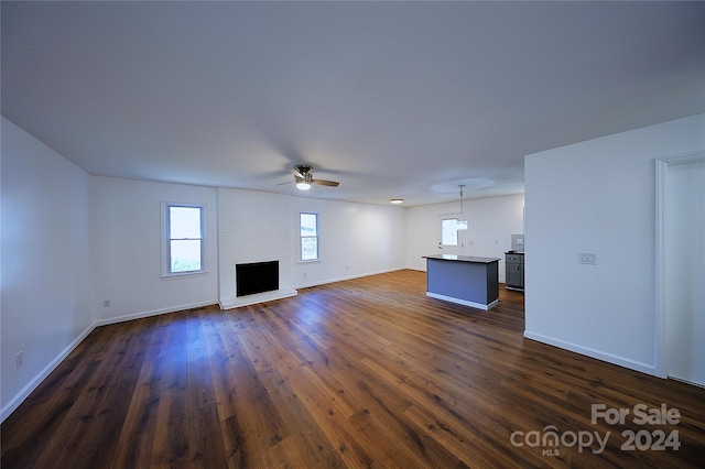 unfurnished living room featuring ceiling fan, dark wood-type flooring, and a brick fireplace