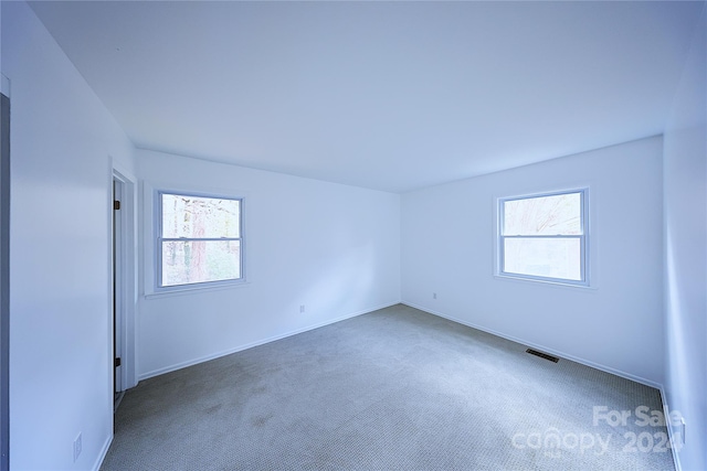 spare room featuring dark colored carpet and a wealth of natural light