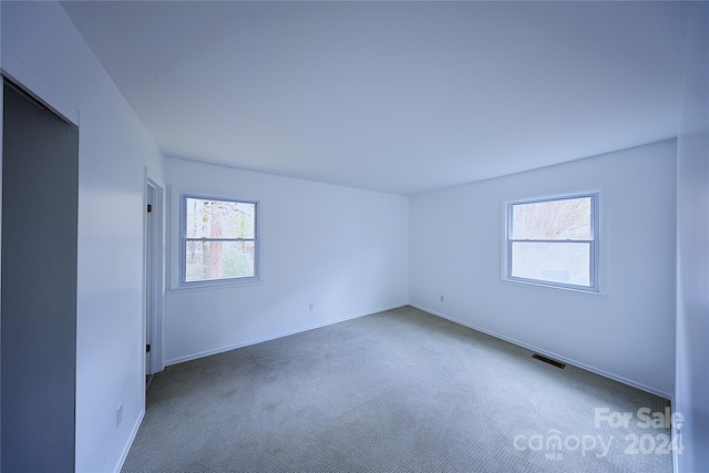 empty room with dark colored carpet and plenty of natural light