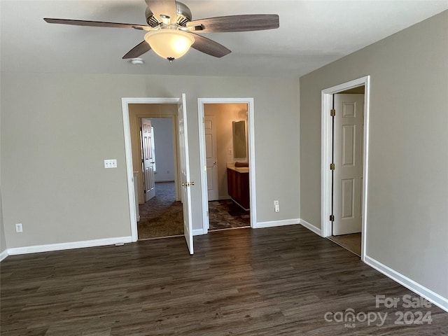 unfurnished bedroom featuring ensuite bath, ceiling fan, and dark wood-type flooring