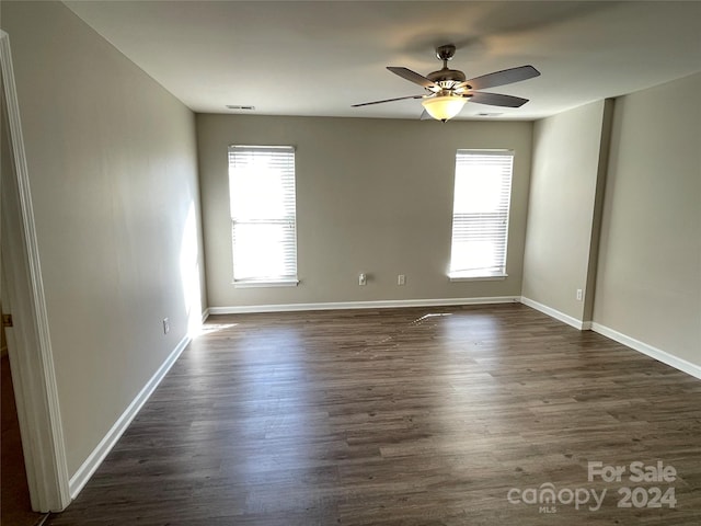 unfurnished room featuring ceiling fan, a healthy amount of sunlight, and dark hardwood / wood-style floors