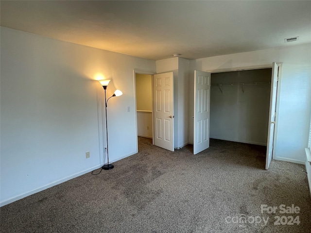 unfurnished bedroom with dark carpet and a closet