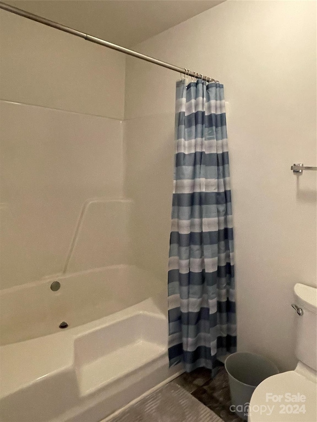 bathroom featuring shower / tub combo and toilet