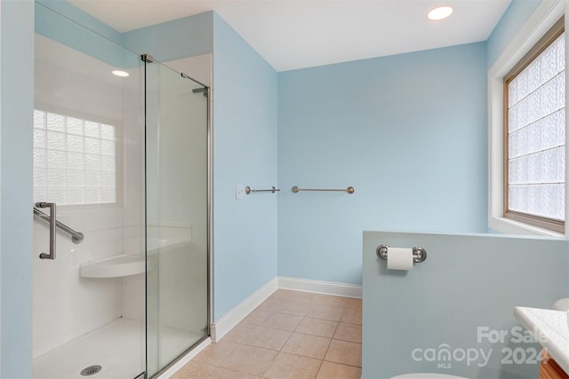 bathroom featuring tile patterned flooring, plenty of natural light, and a shower with shower door